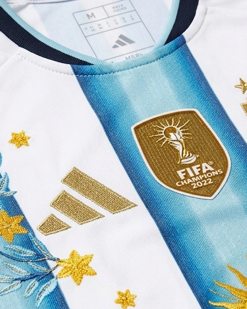 AFA badge with three gold stars and hand-embroidered gold laurel branches on Argentina 2026 home concept jersey — artisanal embroidery Paris & Versailles — VOLTA Sol de Oro Edition