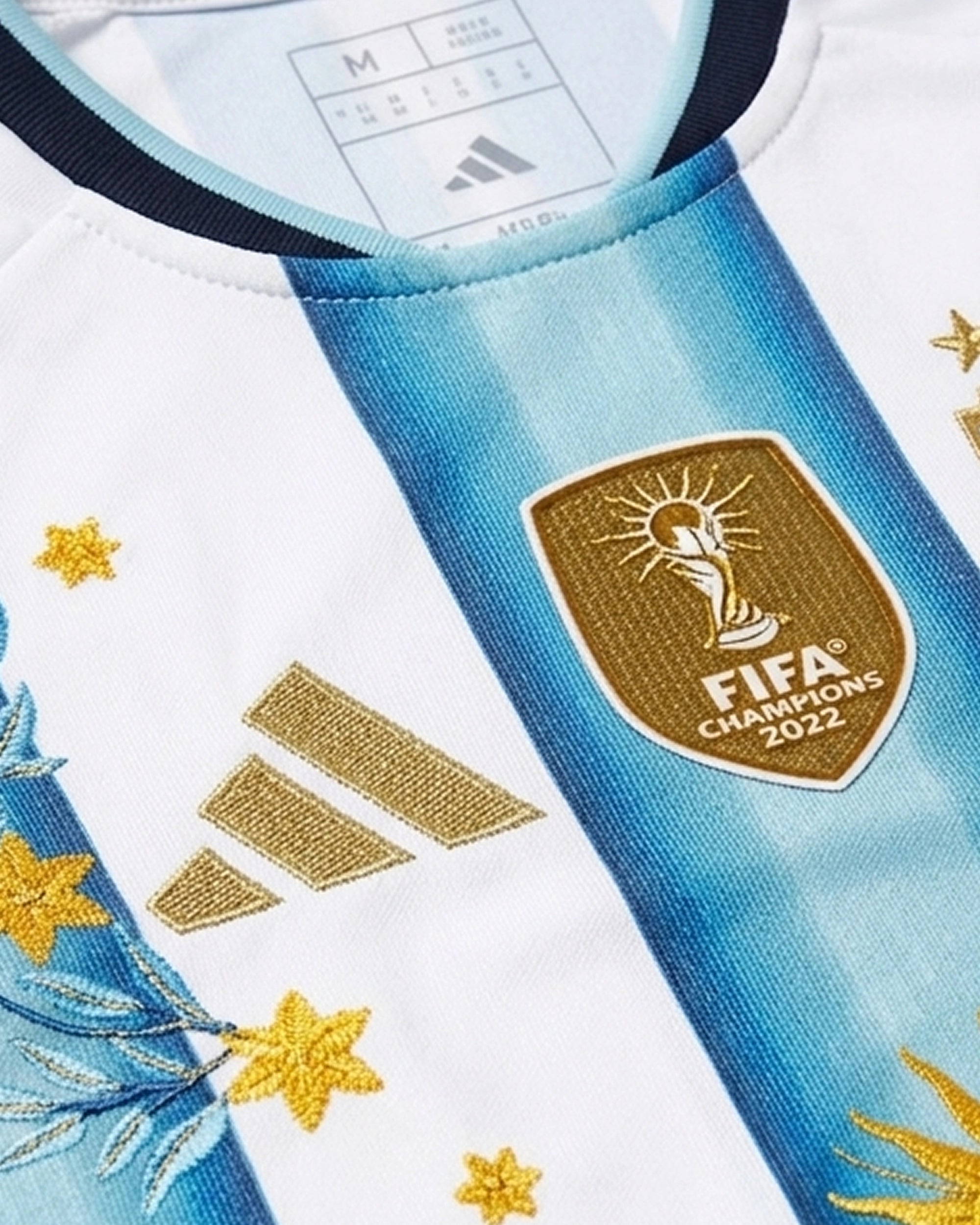 AFA badge with three gold stars and hand-embroidered gold laurel branches on Argentina 2026 home concept jersey — artisanal embroidery Paris & Versailles — VOLTA Sol de Oro Edition