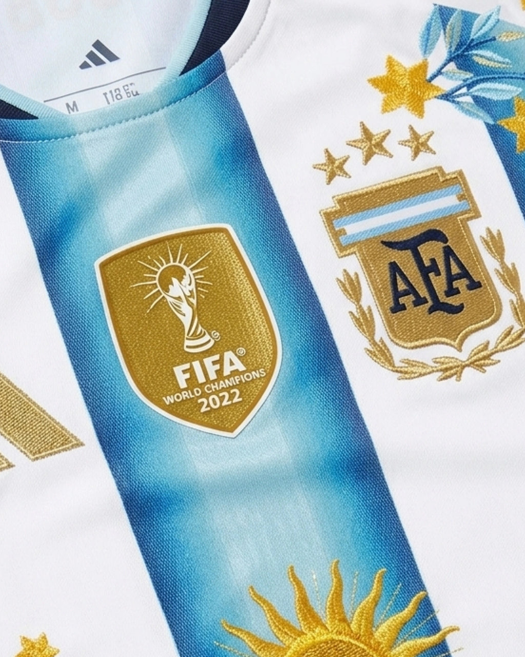 FIFA World Champions 2022 badge with gold hand-embroidered adidas stripes and gold star botanical wreath on Argentina 2026 albiceleste concept jersey — VOLTA Sol de Oro Edition