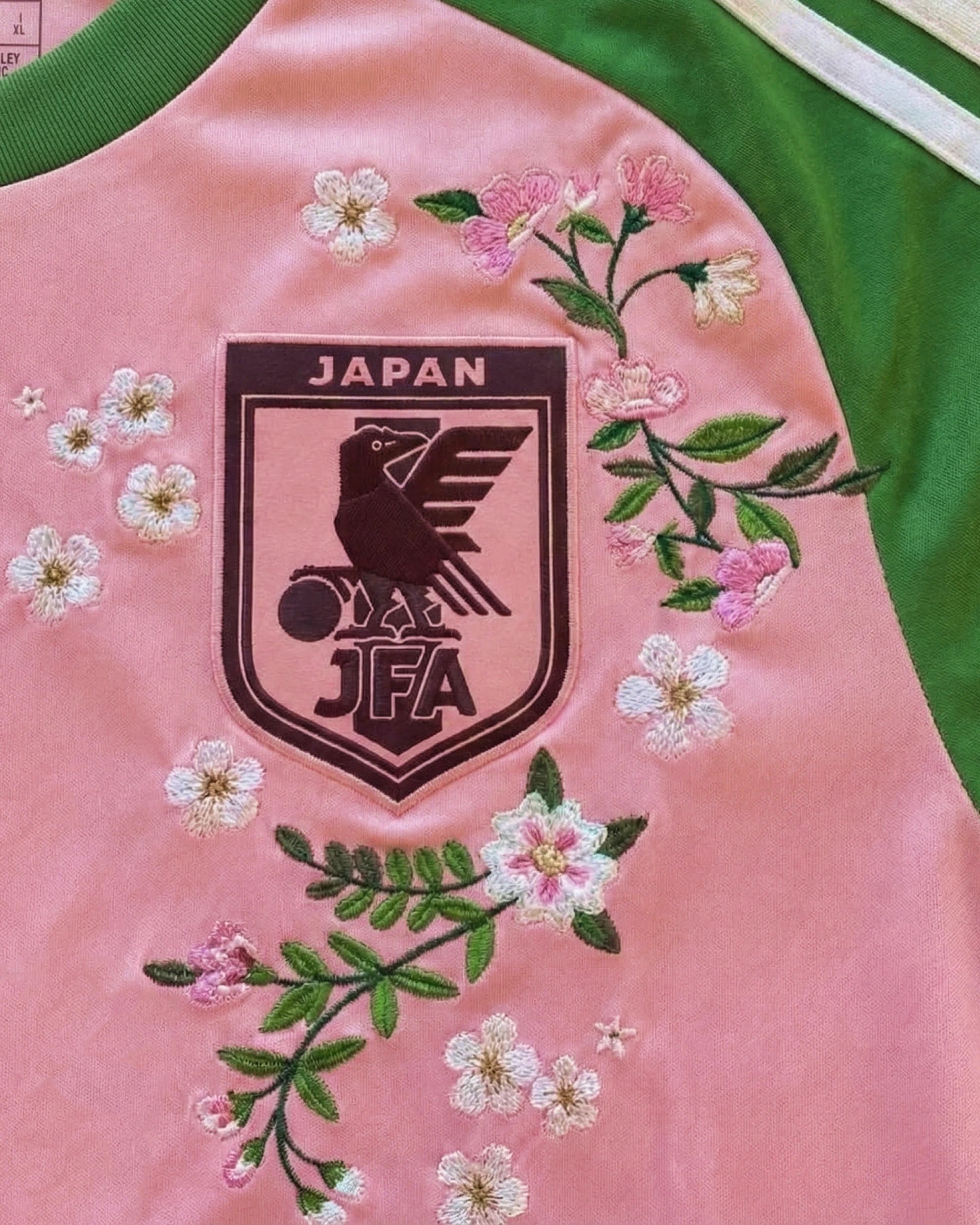 Japan JFA badge detail with hand-embroidered sakura flowers surrounding — custom Japan pink embroidered jersey — VOLTA Sakura Rising Edition