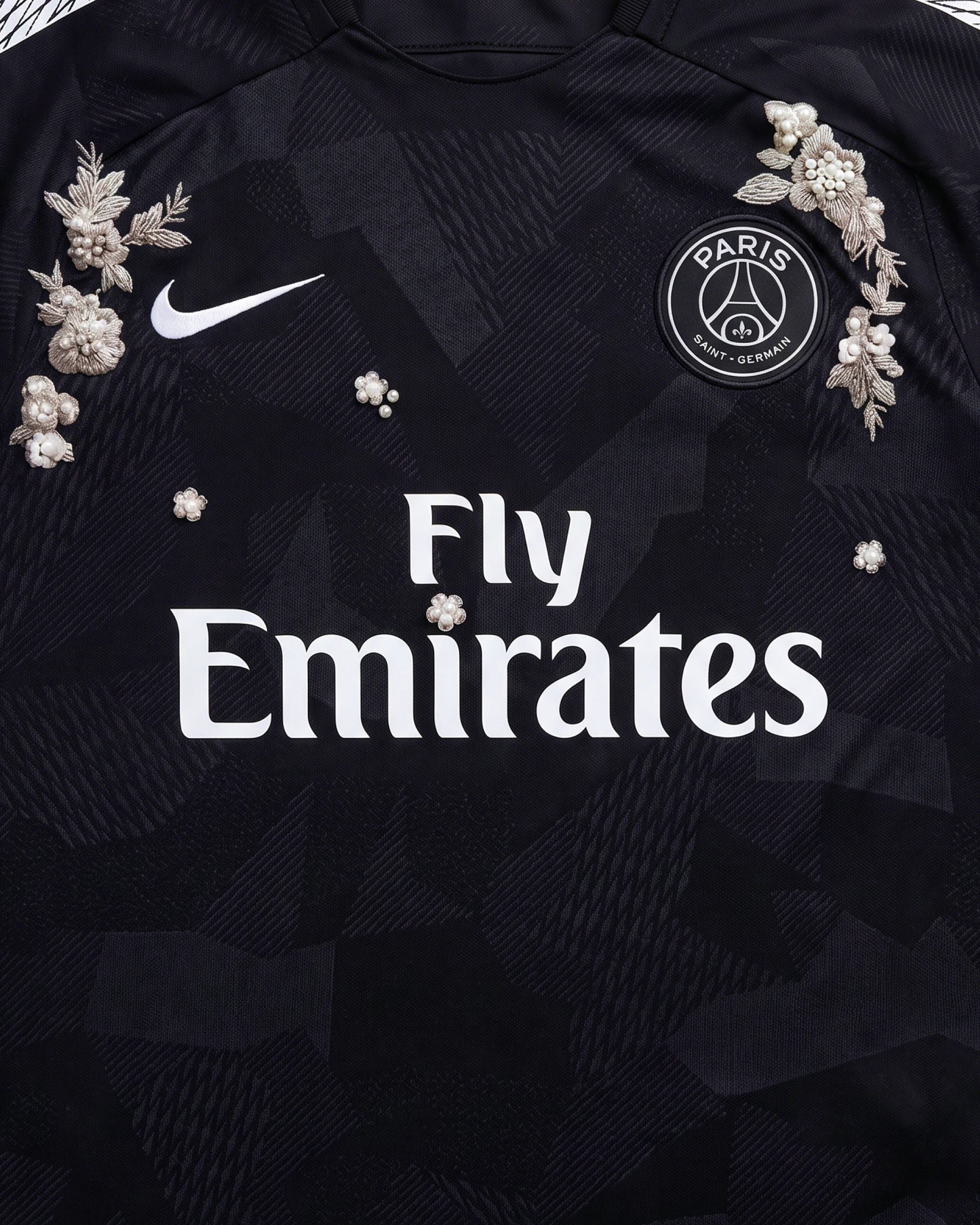 Medium Shot Detail Of the Paris Concept Jersey Chest, Illustrating Symmetrical Silver Botanical Embroidery Encrusted With 3D Pearls Flanking The White Sponsor Text.