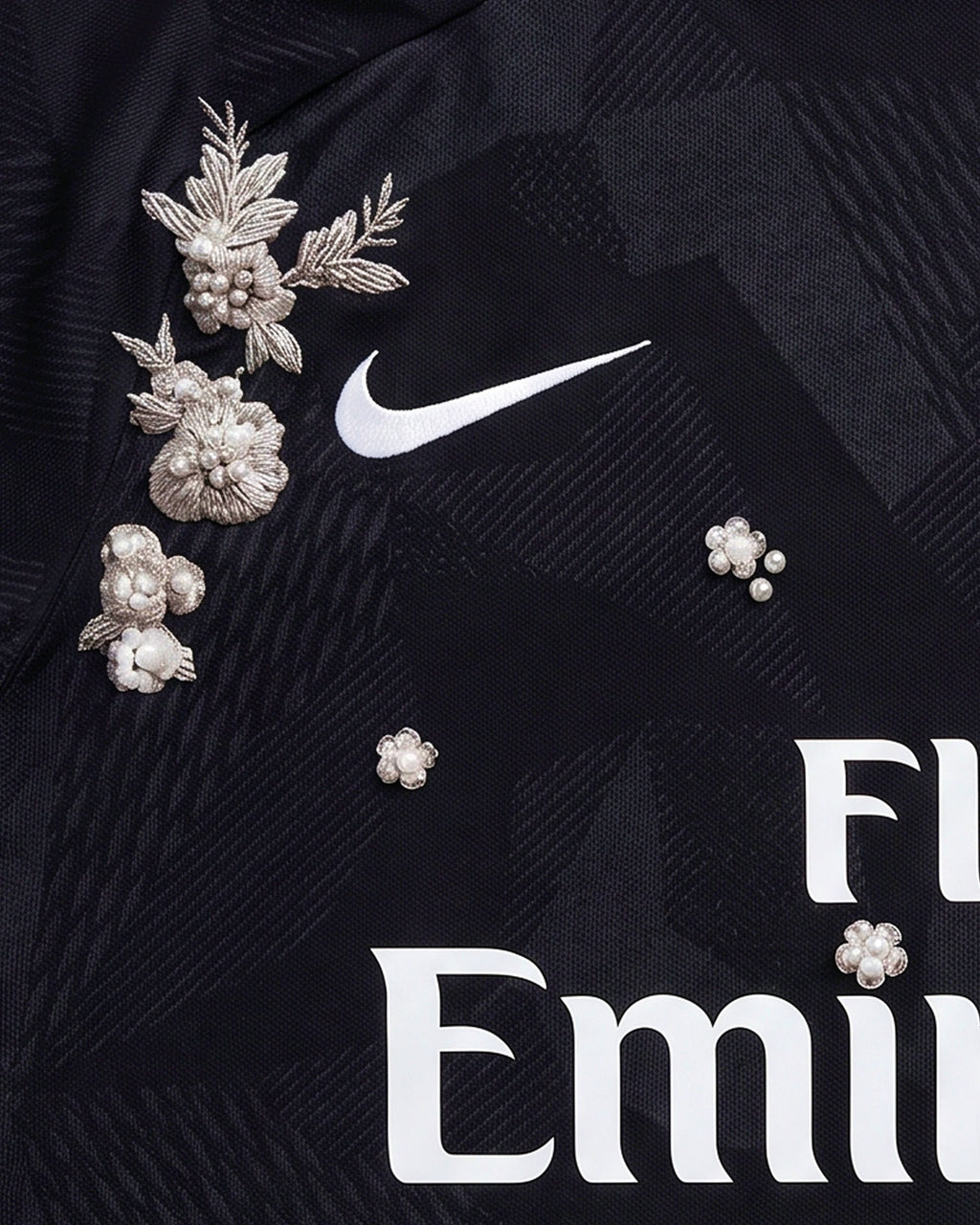 Close-Up Macro Detail Of the Paris Embroidered Black Jersey Crest, Highlighting The High-Density Silver Thread Flowers and Pearl Accents Framing The Circular Team Emblem.