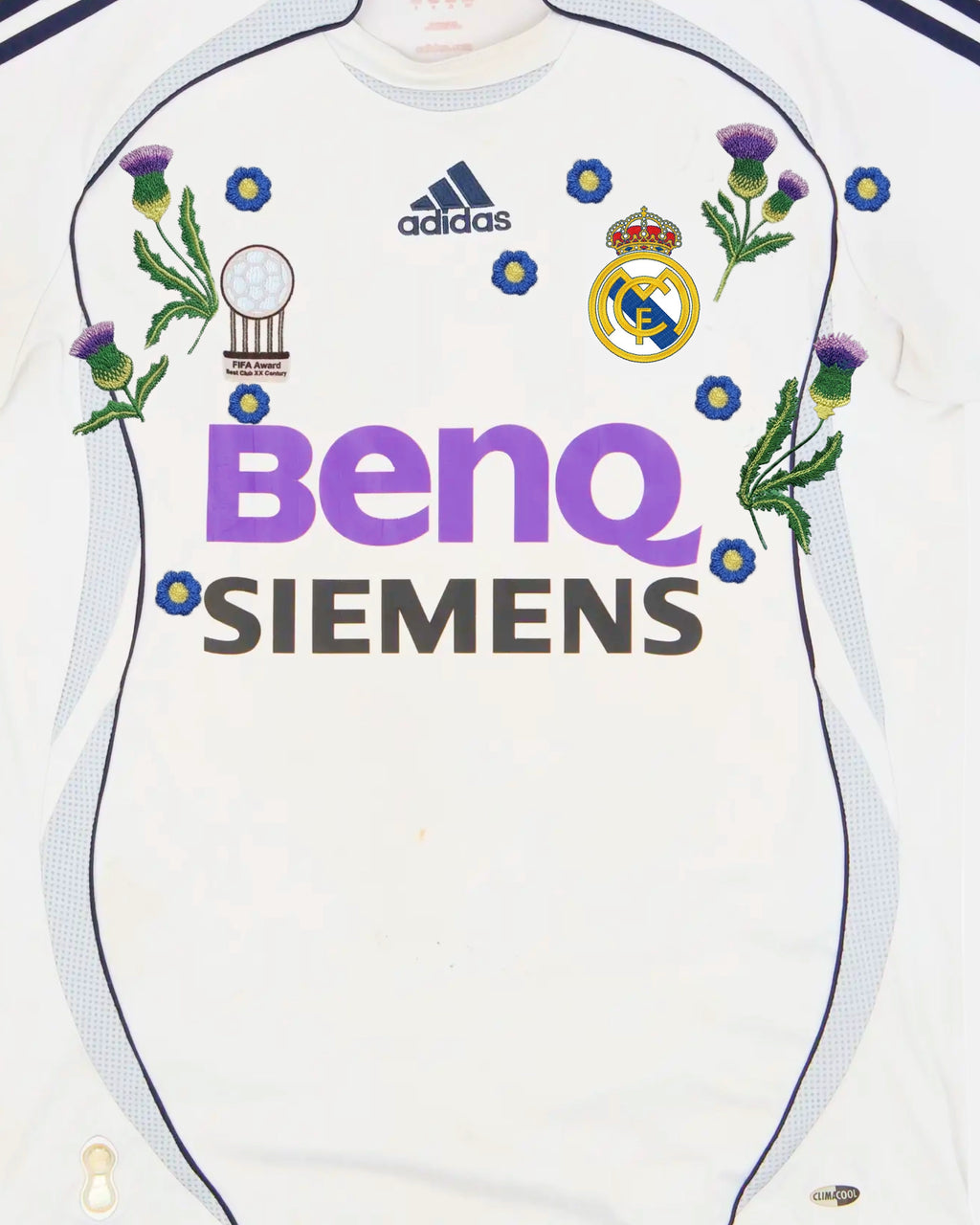 Real Madrid badge surrounded by hand-embroidered Scottish thistles and blue forget-me-not flowers on iconic 2006/07 retro white jersey — botanical embroidery Paris & Versailles — VOLTA
