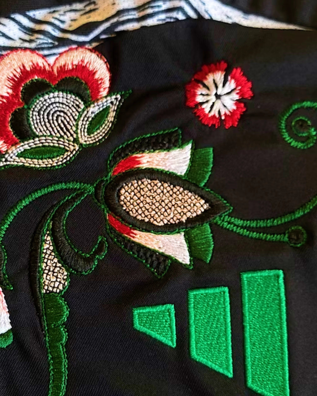Macro Texture Shot Of The Right Shoulder On The Custom Embroidered Black Arsenal Shirt, Showcasing The Dense Haptic 3D Thread Quality Of A Crimson Carnation Next To The Side Graphic.