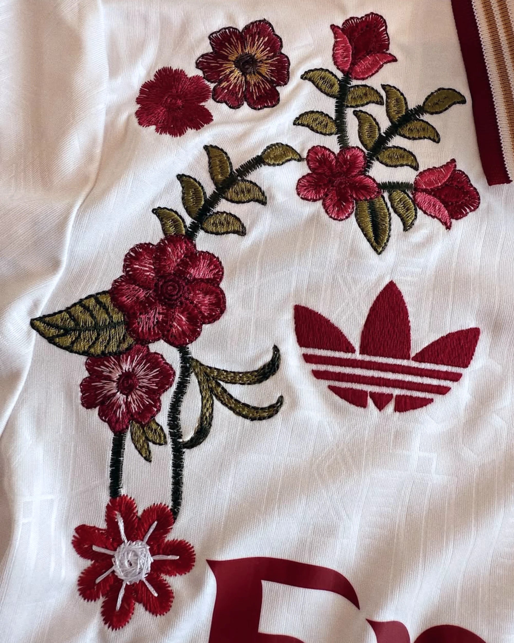 Arsenal cannon badge close-up with hand-embroidered rose and floral art — custom Arsenal embroidered jersey — VOLTA