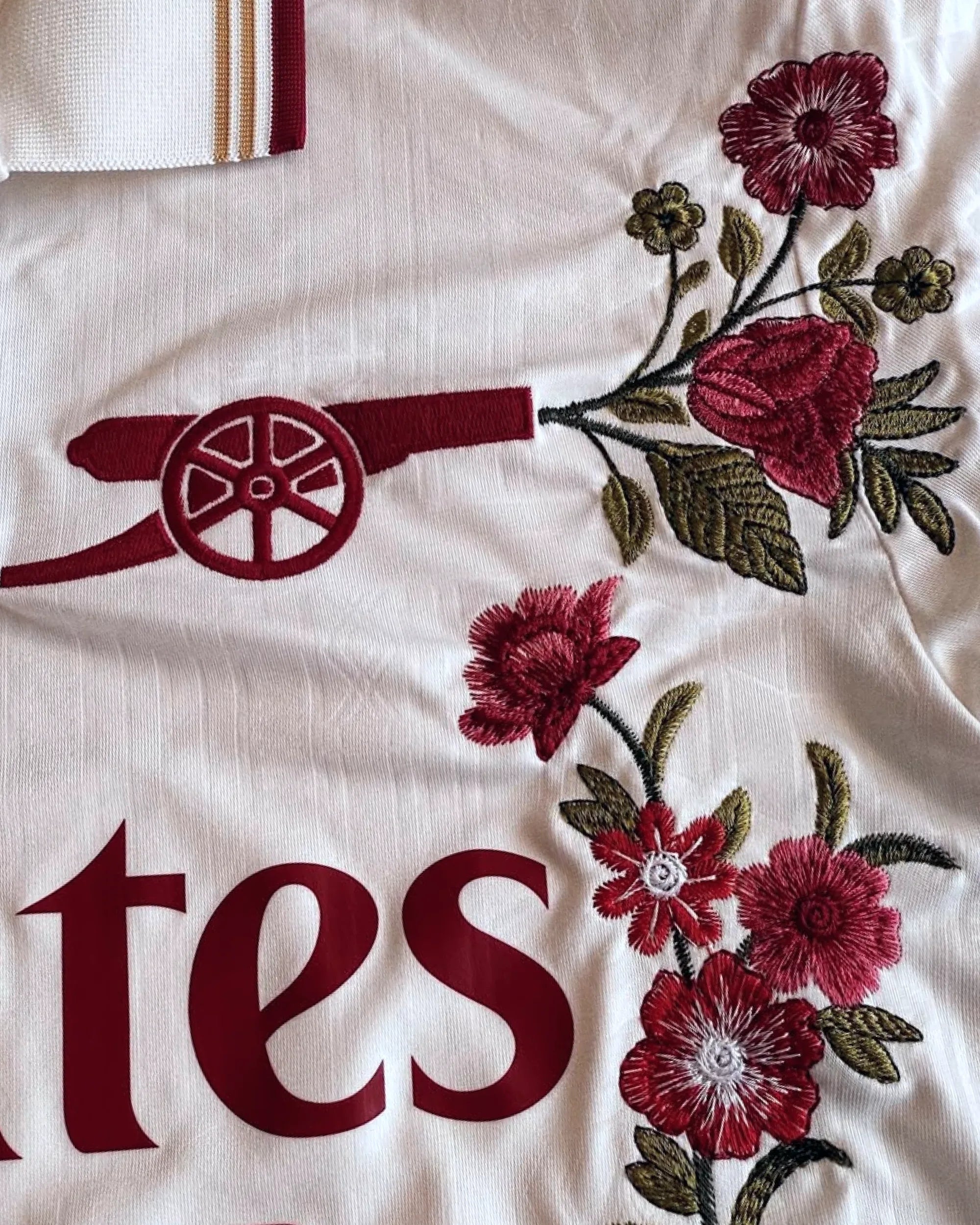 Arsenal white jersey badge detail with hand-embroidered botanical flowers — VOLTA Gunners Garden Edition