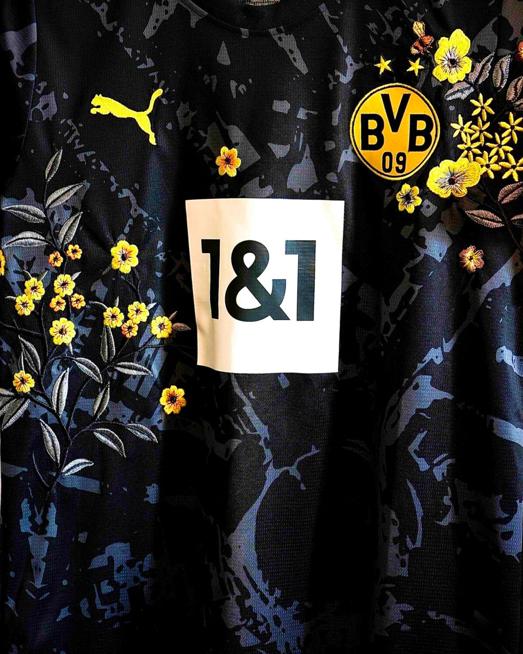 Medium Chest Shot Detail Of The Borussia Dortmund Concept Jersey, Showcasing Symmetrical Yellow Primrose Embroidery Framing The Central White Sponsor Block.