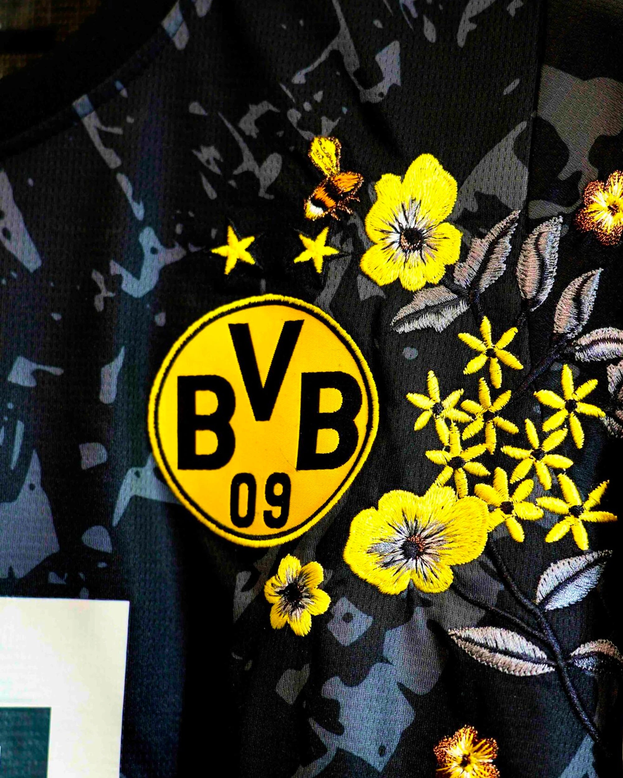 Close-Up Macro Shot Of the Left Chest On the BVB Cup Kit Revisited, Highlighting The Premium Embroidered Honeybee Graphic Flying Above the Two-Starred Yellow Club Crest.