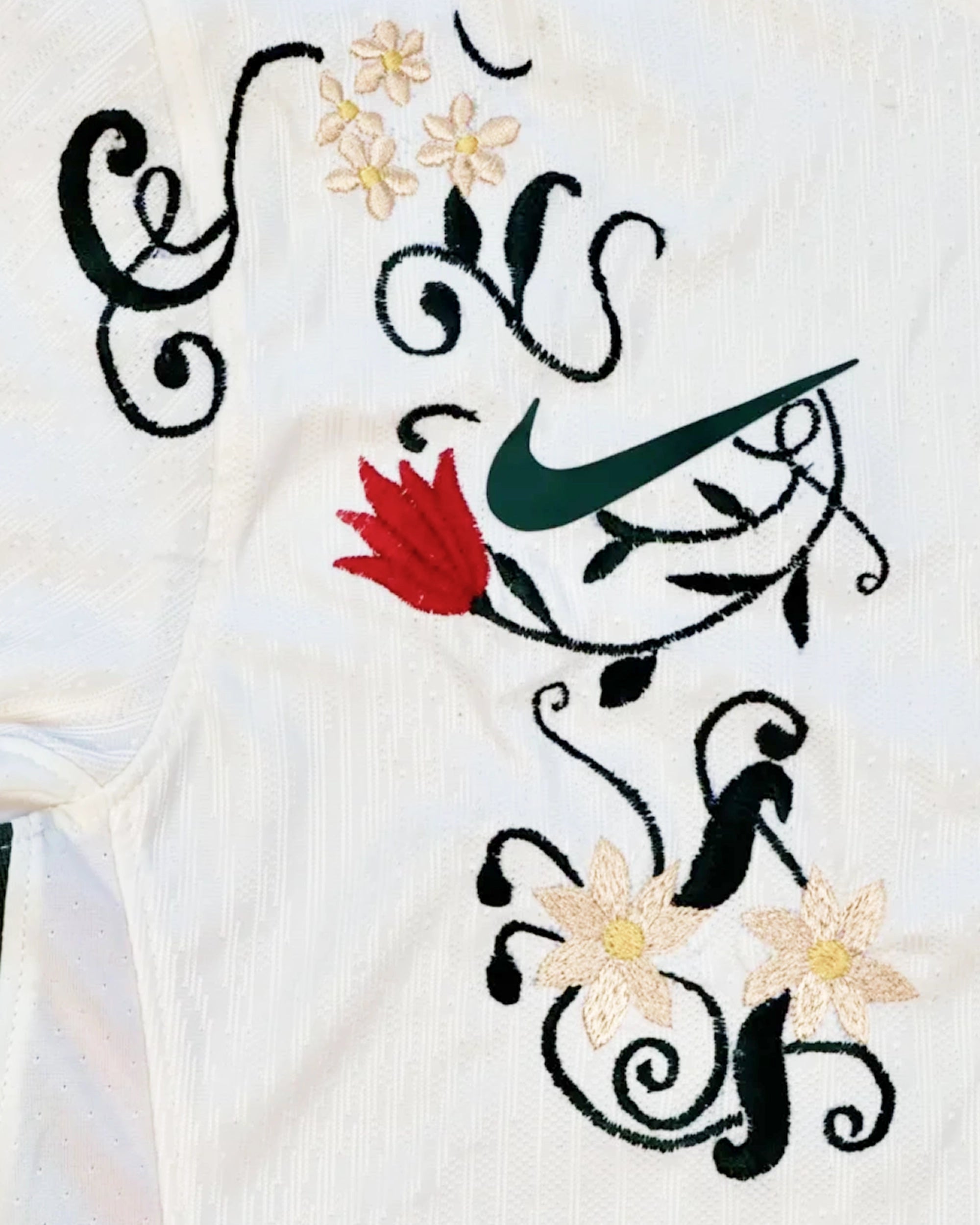 Macro Texture Shot Focusing On the Right Chest Of the Custom Embroidered White Chelsea Shirt, Highlighting Dense Crimson Tulips and Cream Flowers Over the Brand Logo.