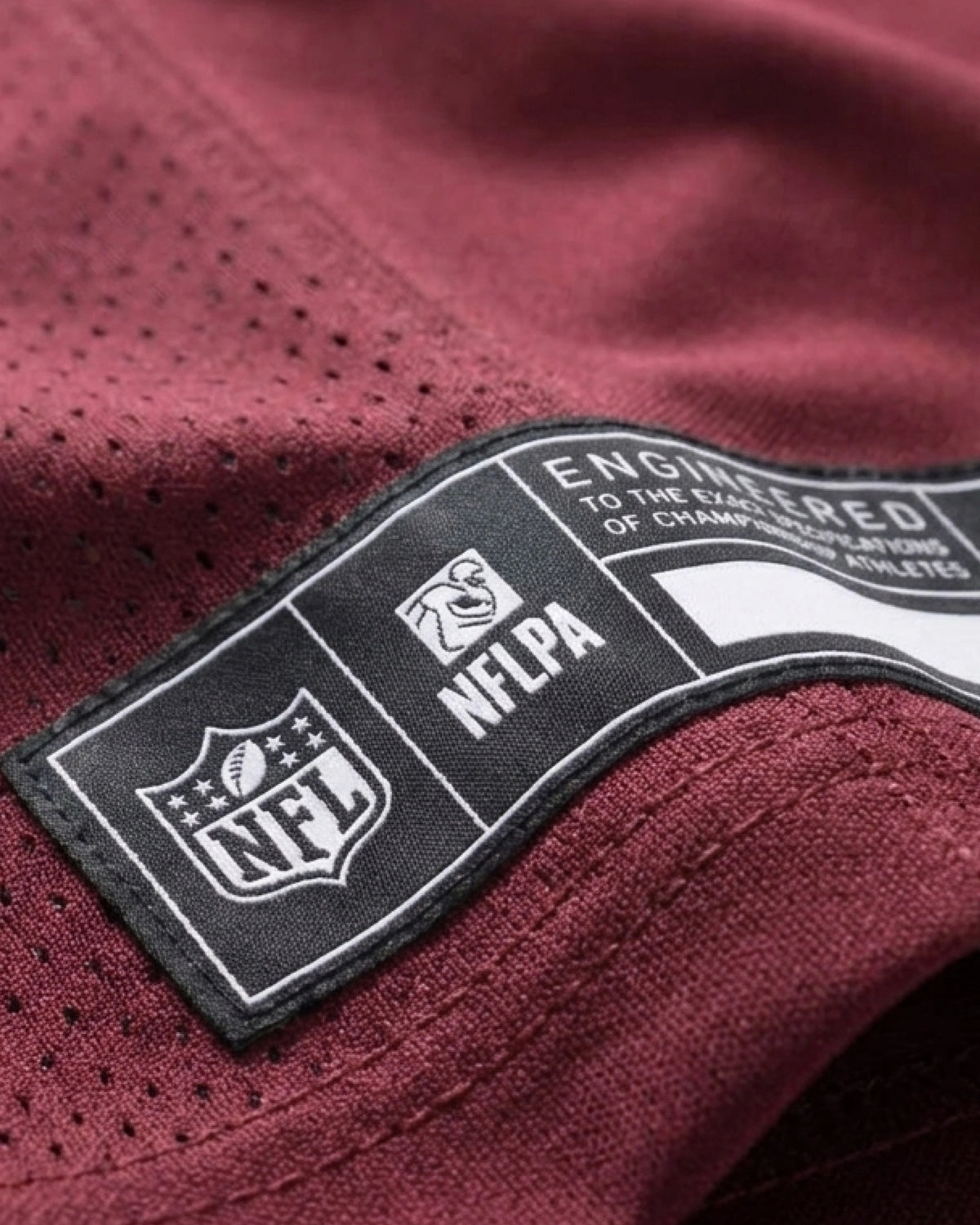 Macro Detail Shot Of The Official Engineered Authenticity Patch On The Hem Of The PSG x NFL Custom Jersey, Highlighting Premium Finishing Elements.