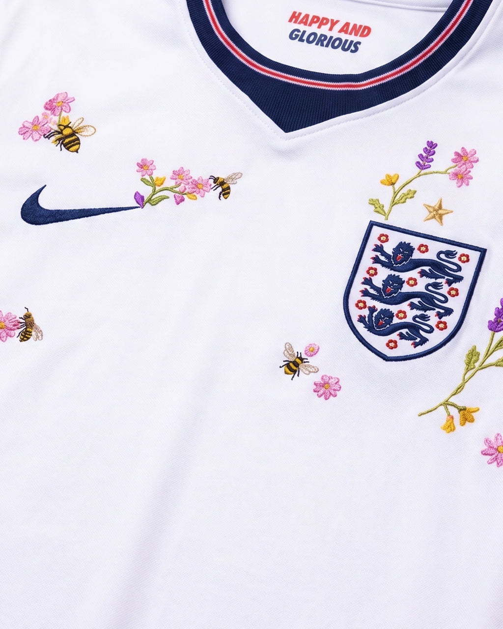 England Three Lions badge surrounded by hand-embroidered honey bees, pink wildflowers, purple lavender and gold star botanical art on white concept jersey — VOLTA Happy and Glorious Edition Paris & Versailles