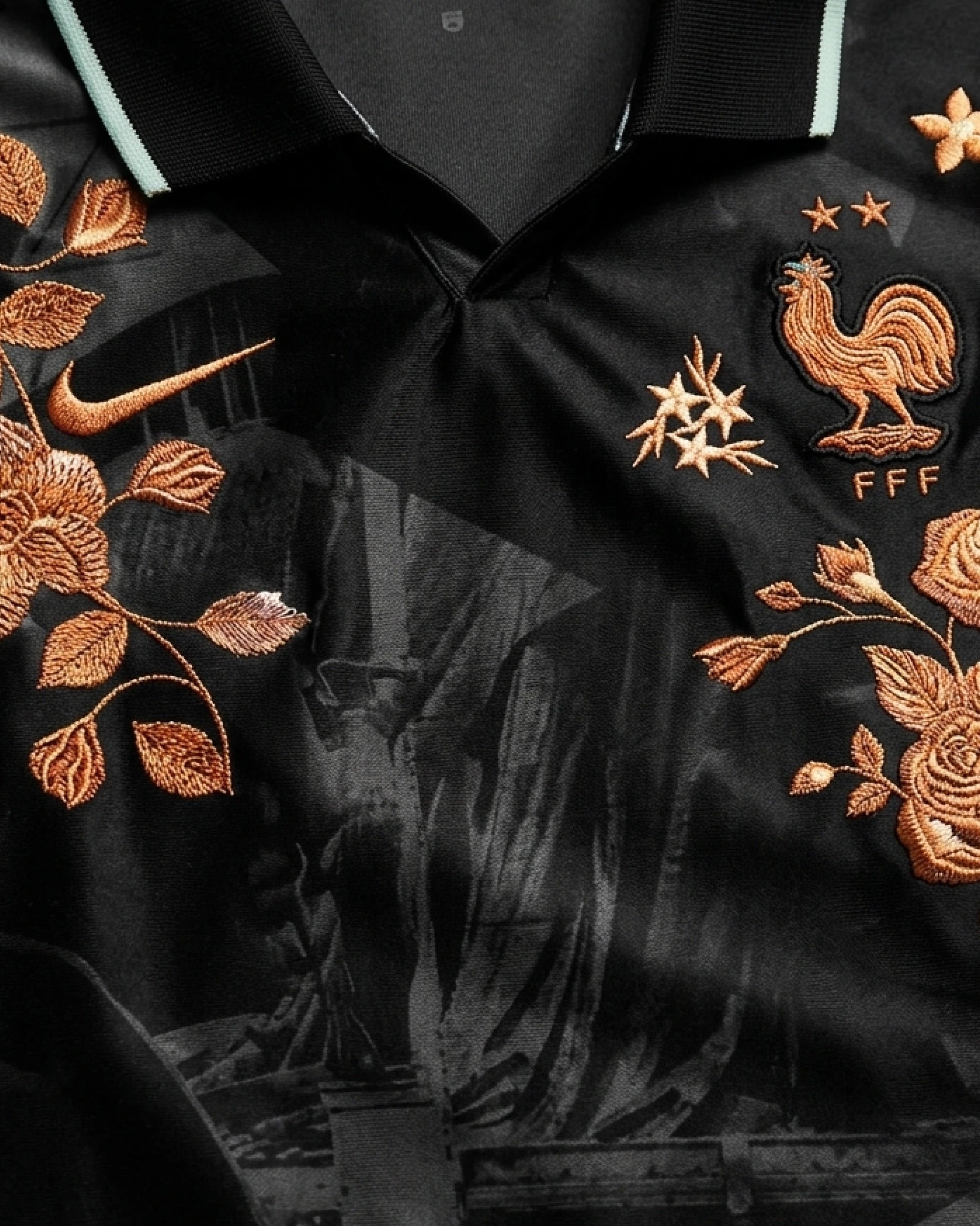 FFF rooster badge close-up with hand-embroidered gold star cluster and bronze rose botanical art on France black concept jersey — VOLTA Nos Différences Edition Paris & Versailles