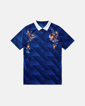 Full Front View Of The Bespoke France World Cup 2026 Jersey Reimagined, Showcasing The Blue Geometric Base, White Polo Collar, And Coppery Floral Embroidery.