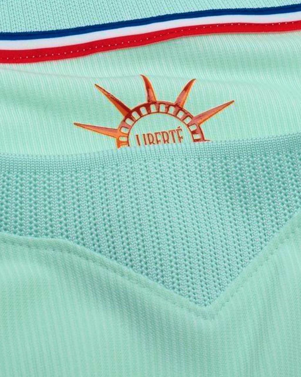 Close-up macro detail of the inner collar of the France World Cup Jersey Revisited, showcasing the orange sun emblem printed with the word Liberte.