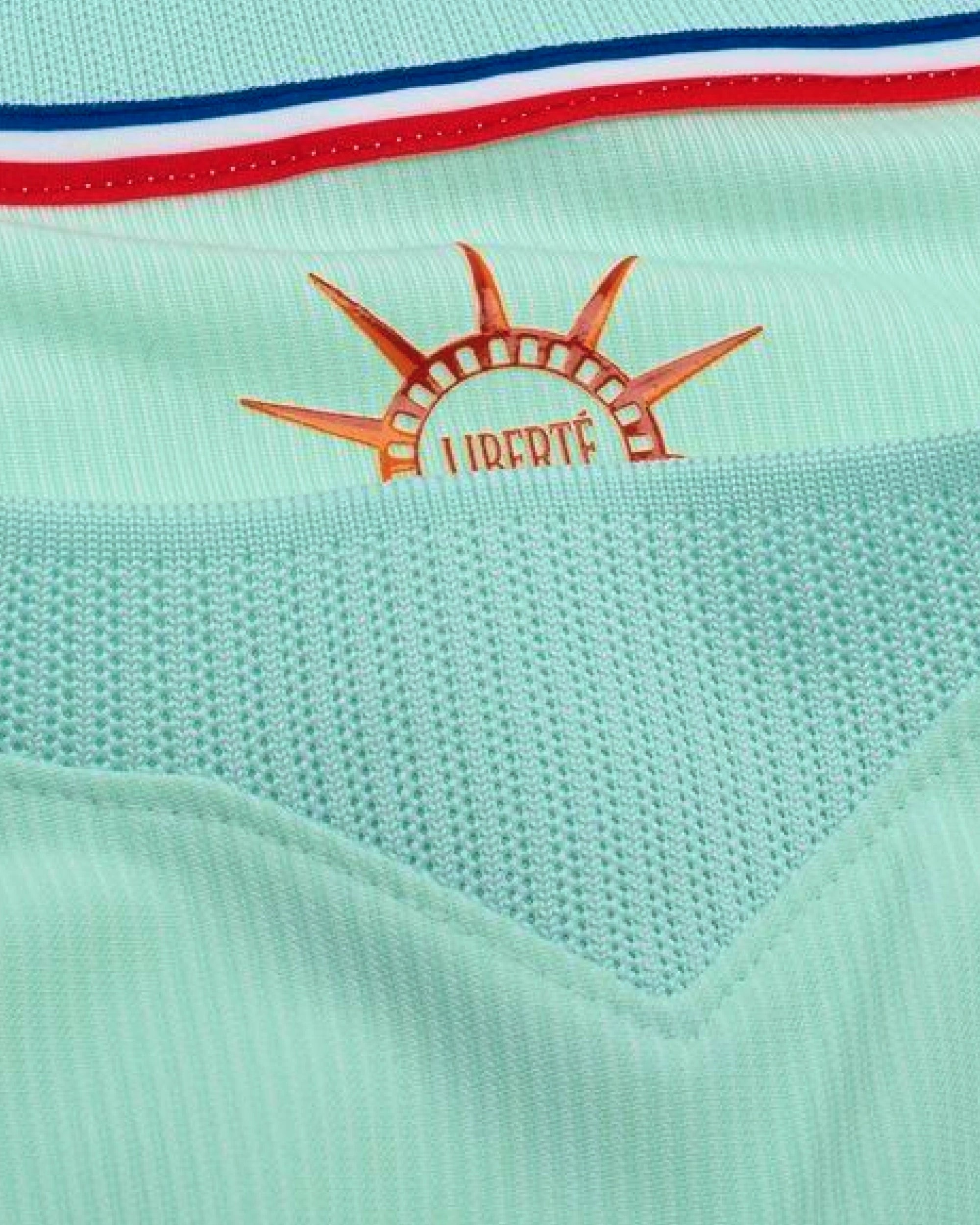 Close-up macro detail of the inner collar of the France World Cup Jersey Revisited, showcasing the orange sun emblem printed with the word Liberte.