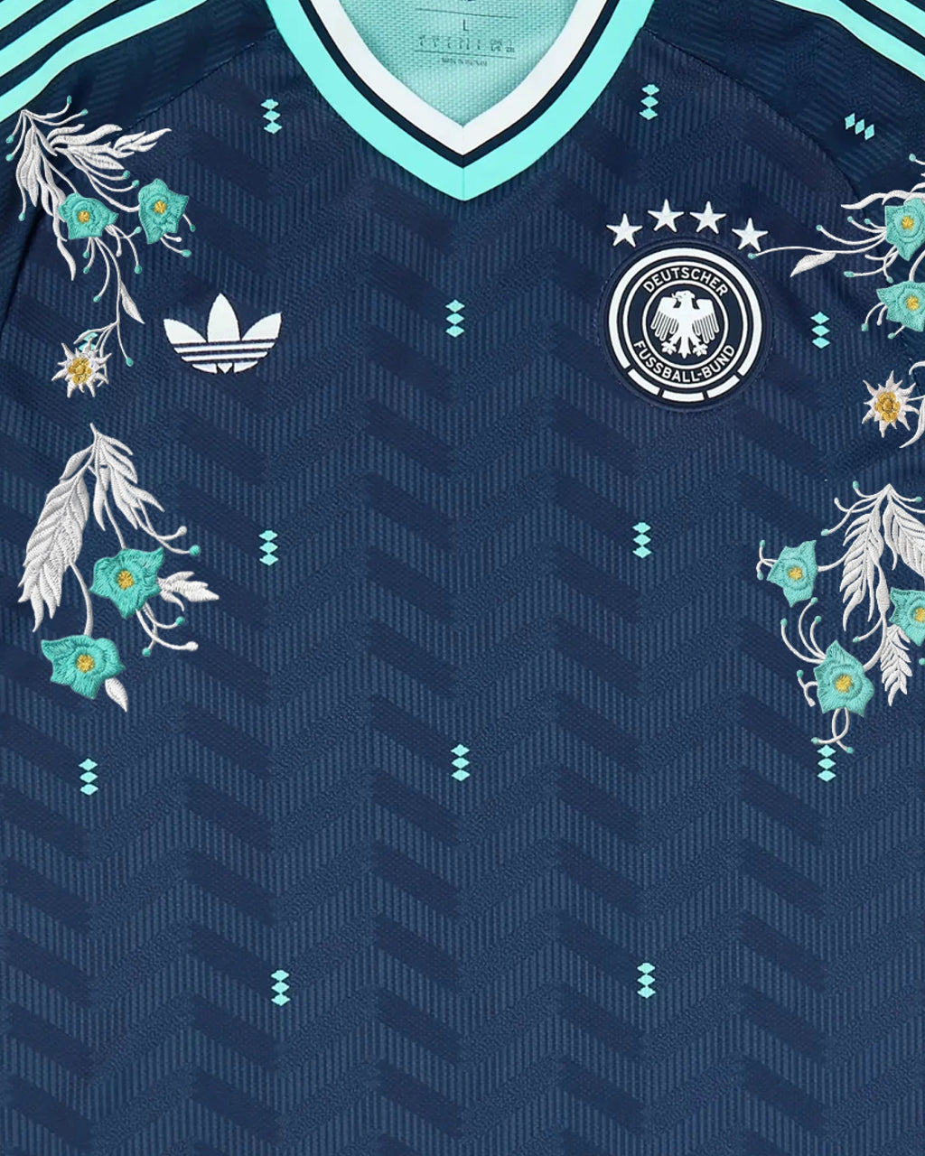 Upper Torso Centered Shot Of The Germany Embroidered Jersey 2026, Displaying The Balanced Composition of Silver Foliage and Mint Flowers Across Both Crests.