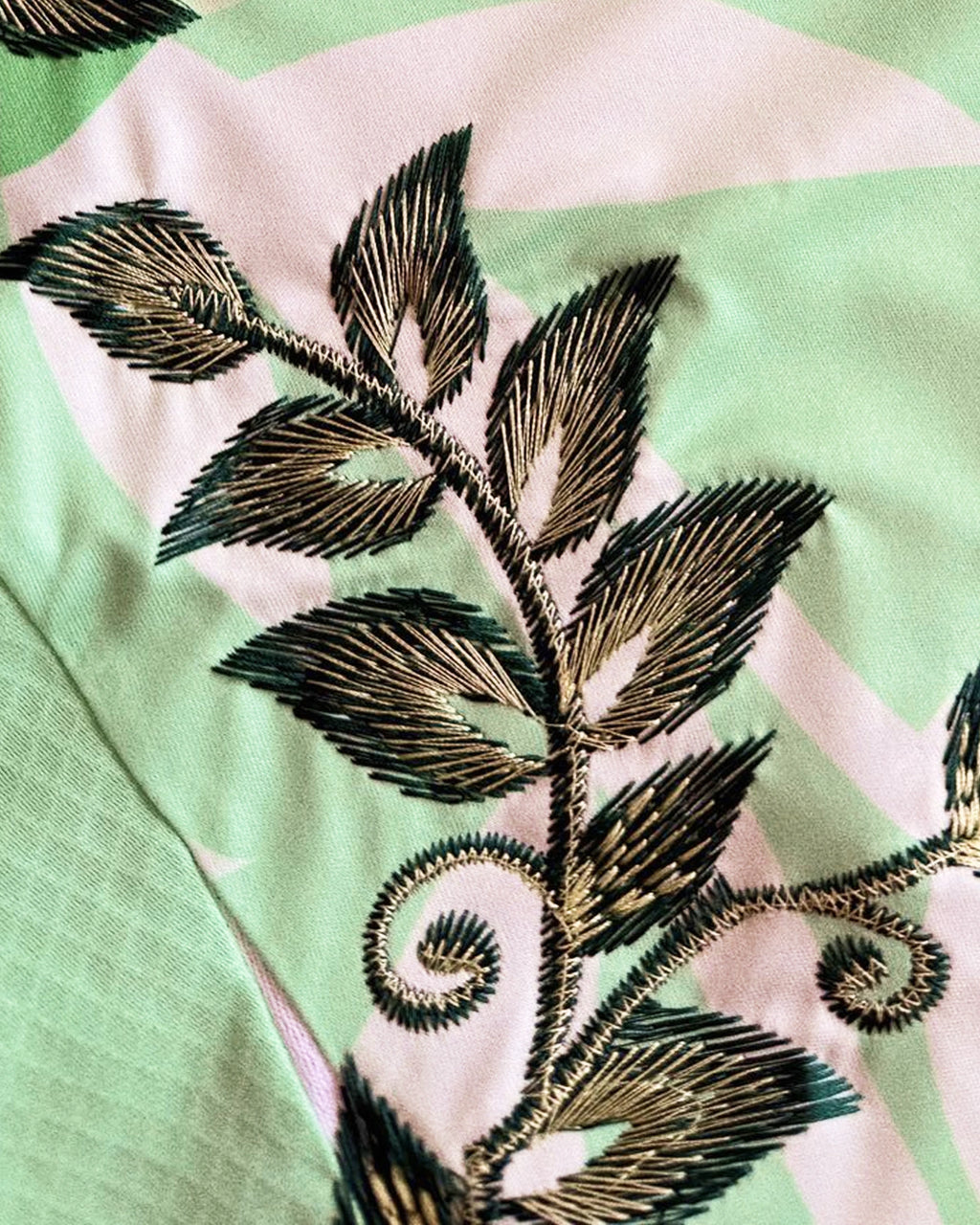 Close-Up Detail Shot Of The Hand-Guided Leaf Stitching, Showcasing Premium Metallic Bronze and Deep Forest Green Gradients On The Mint Sportswear Grid.