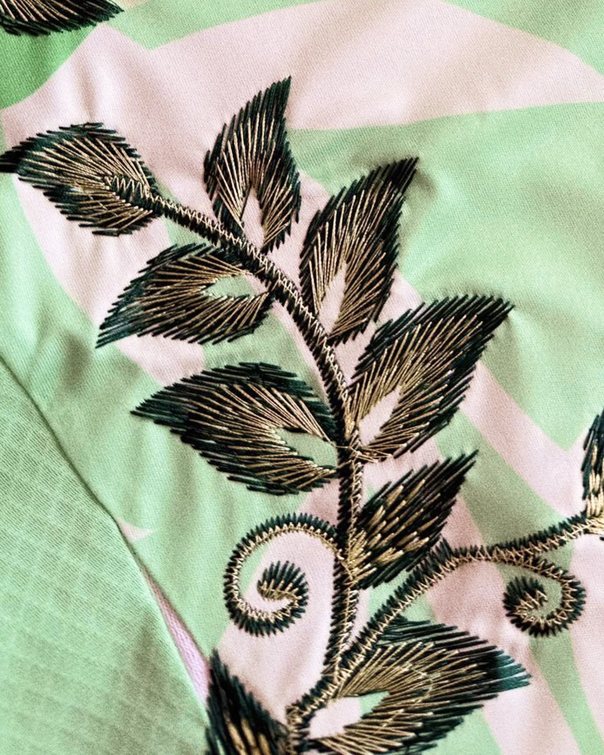 Close-Up Detail Shot Of The Hand-Guided Leaf Stitching, Showcasing Premium Metallic Bronze and Deep Forest Green Gradients On The Mint Sportswear Grid.
