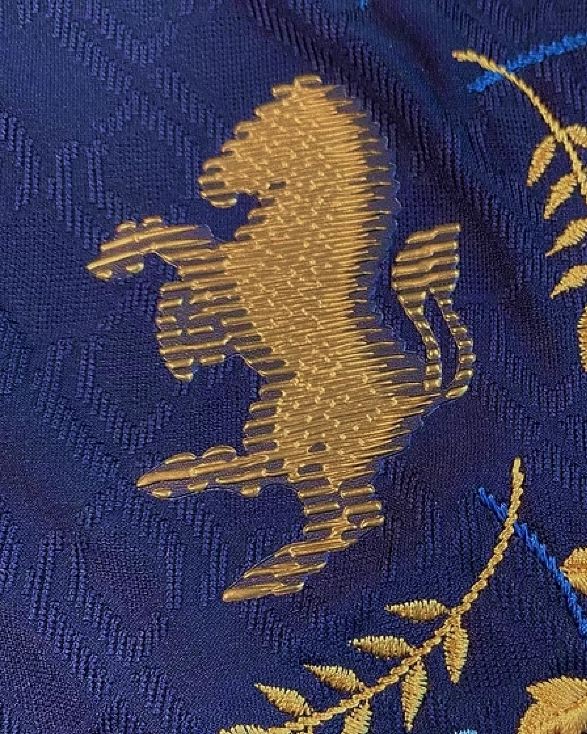 Macro Texture Shot Of The Right Chest On The Juventus Embroidered Blue Jersey, Highlighting Symmetrical Multi-Tonal Blue And Gold Botanical Floral Patterns.