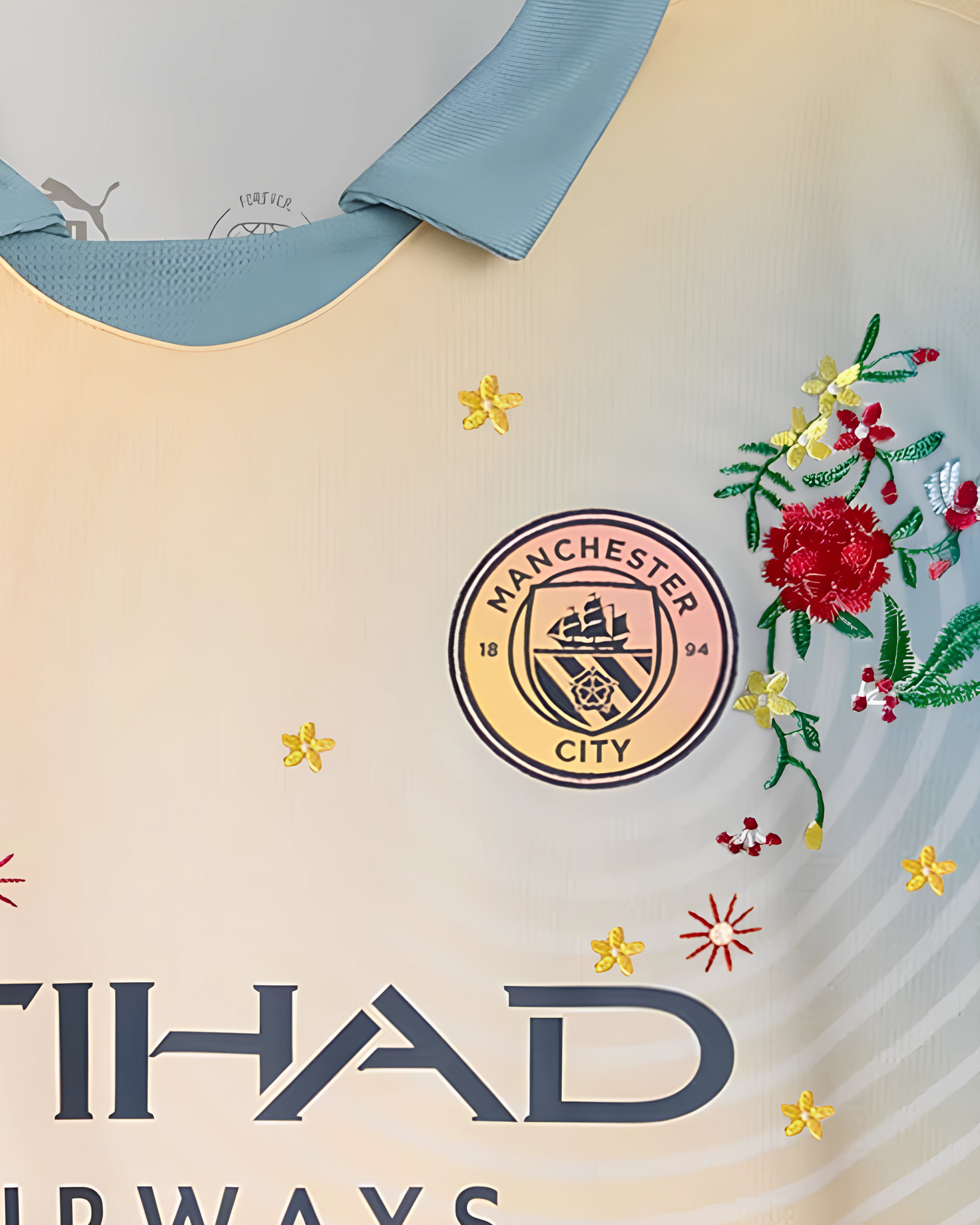 Close-Up Macro Detail On The Right Chest Of The Manchester City Concept Jersey, Illustrating Dense Crimson Carnation Stitches and Scattered Gold Stars Over The Brand Logo.