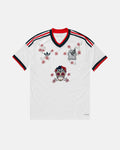 Full Front View Of The Bespoke Mexico World Cup 2026 Jersey Reimagined, Showcasing The White Base, Tricolor Cuffs, Crimson Floral Vines, And Center Sugar Skull.