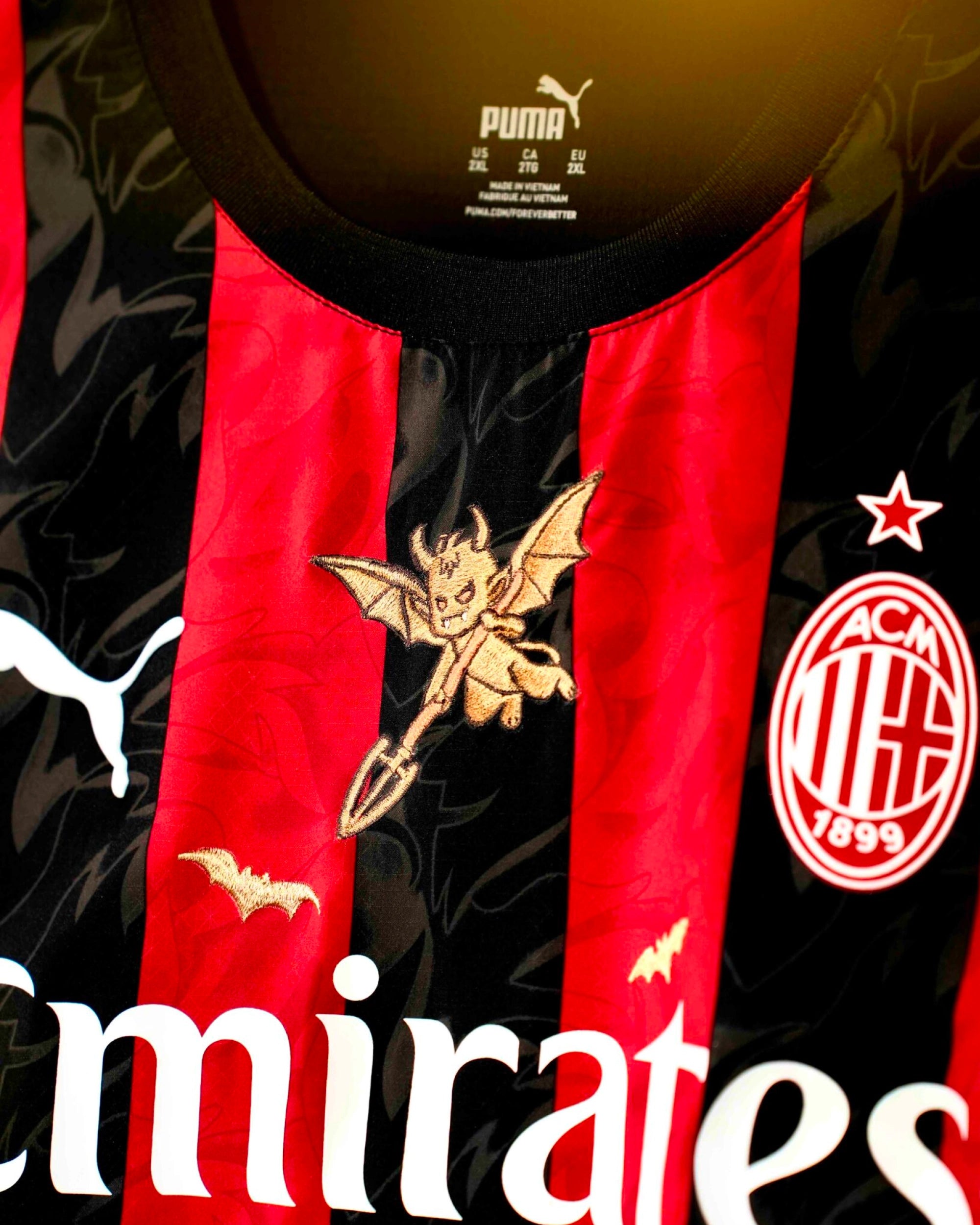 Close-Up Macro Shot Focus On The Upper Chest Of The Milan Home Kit Revisited, Highlighting The Dense Haptic 3D Thread Quality Of The Hand-Guided Golden Little Devil Graphic.