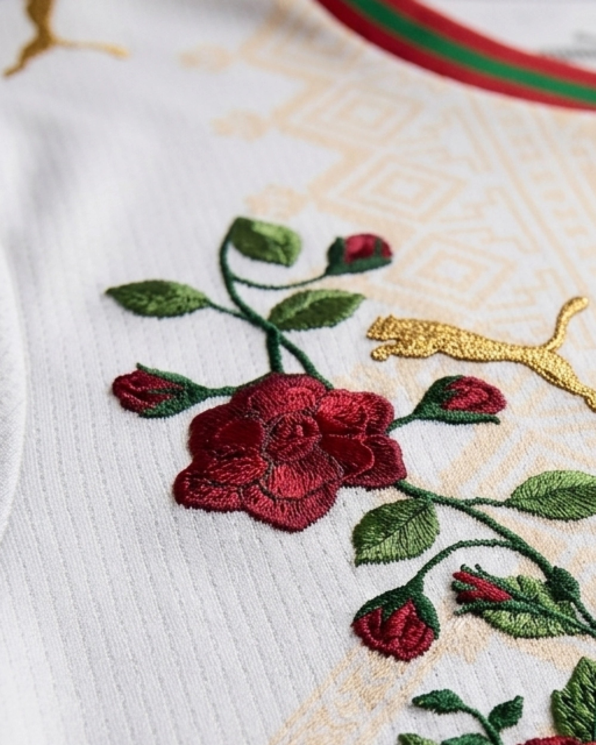Hand-embroidered deep crimson rose bloom beside gold kit logo on Amazigh geometric panel — Morocco 'Atlas Rose' Edition — VOLTA Paris