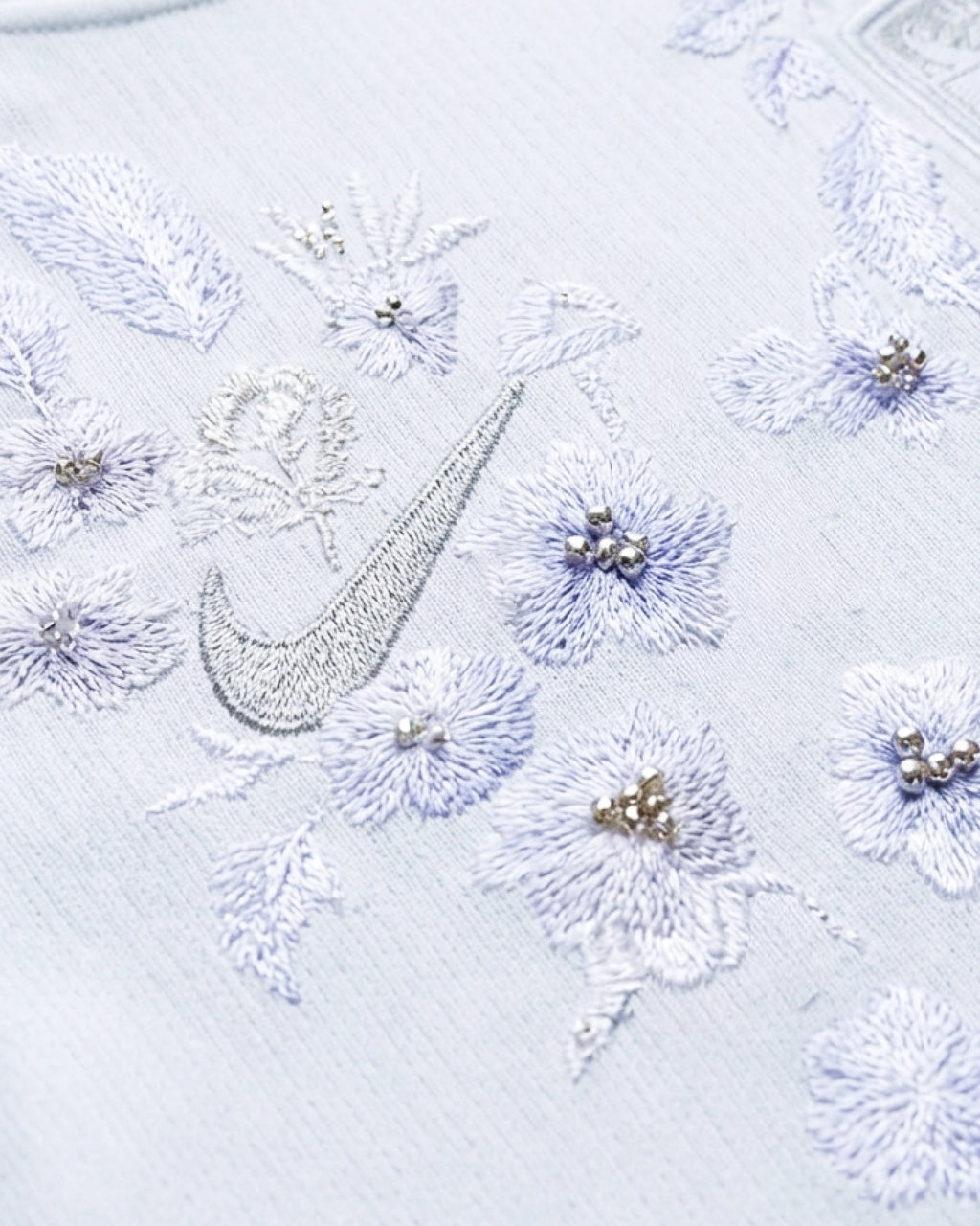 Macro detail of the artisan hand-guided embroidery on the Norway World Cup Jersey, showcasing the haptic 3D texture of silver threads and delicate hand-applied pearls mimicking frost.